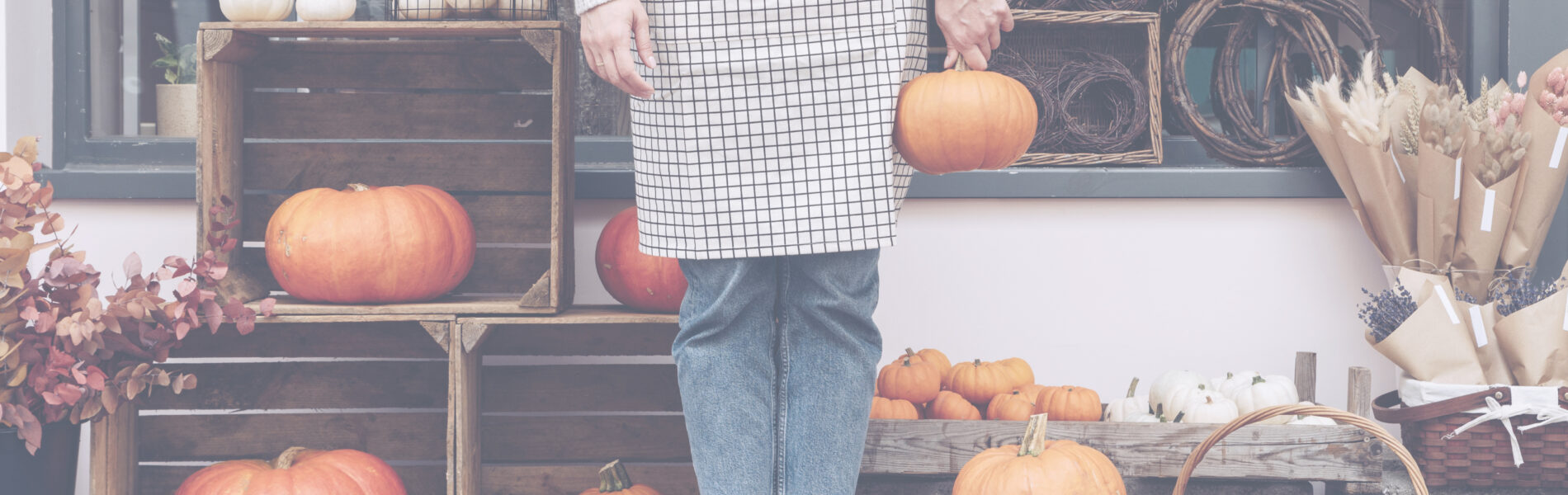 Woman holding halloween pumpkin at her flower shop. Fall autumn